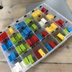 Farvede LEGO-klodser med bogstaver og tal i opbevaringsboks til undervisning og leg.