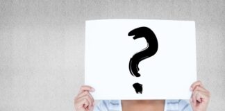 Leder: Med chefens øjne Et billede af en kvinde der holder et skift med et spørgsmålstegn op foran sit ansigt