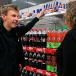 Fra fritid til fremtid Ung mand står ved hylder i supermarked med sodavand. Han snakker med en kollega