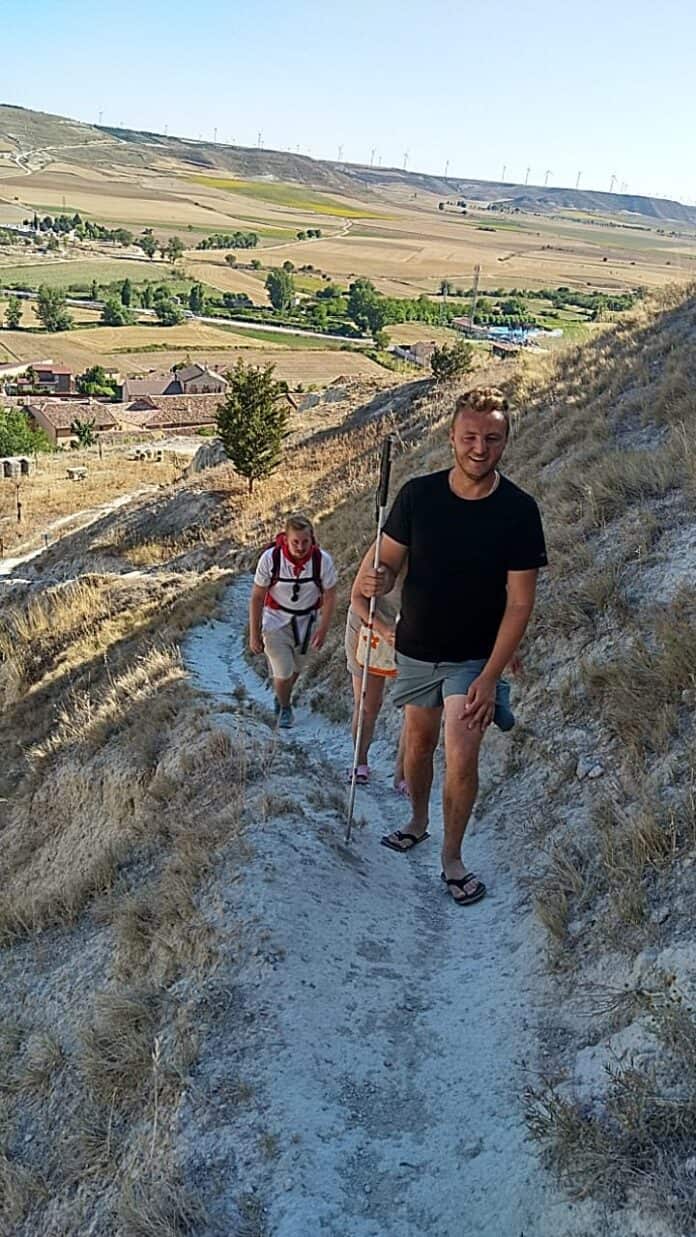 Edis Adilovic går på en sti på en bakke i et åbent landskab på den franske del af Caminoen i Pyrenæerne. Han har sin blindestok i hånden