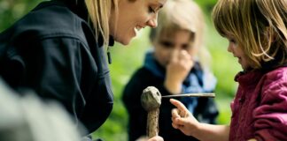 Fra frygt til frirum to små børn leger med en naturvejleder og laver en lerfigur på en pind