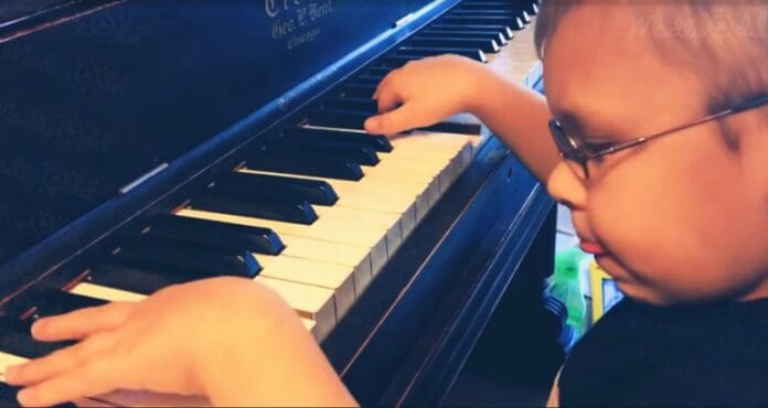 lille dreng med briller øver sig i at spille på klaver