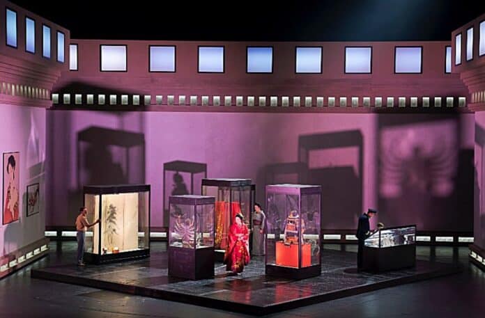 Scene fra Operaen Madam Butterfly på Det Kgl Teater, der er synstolket. Fire glasmontrer står i et lilla rum med rød belysning
