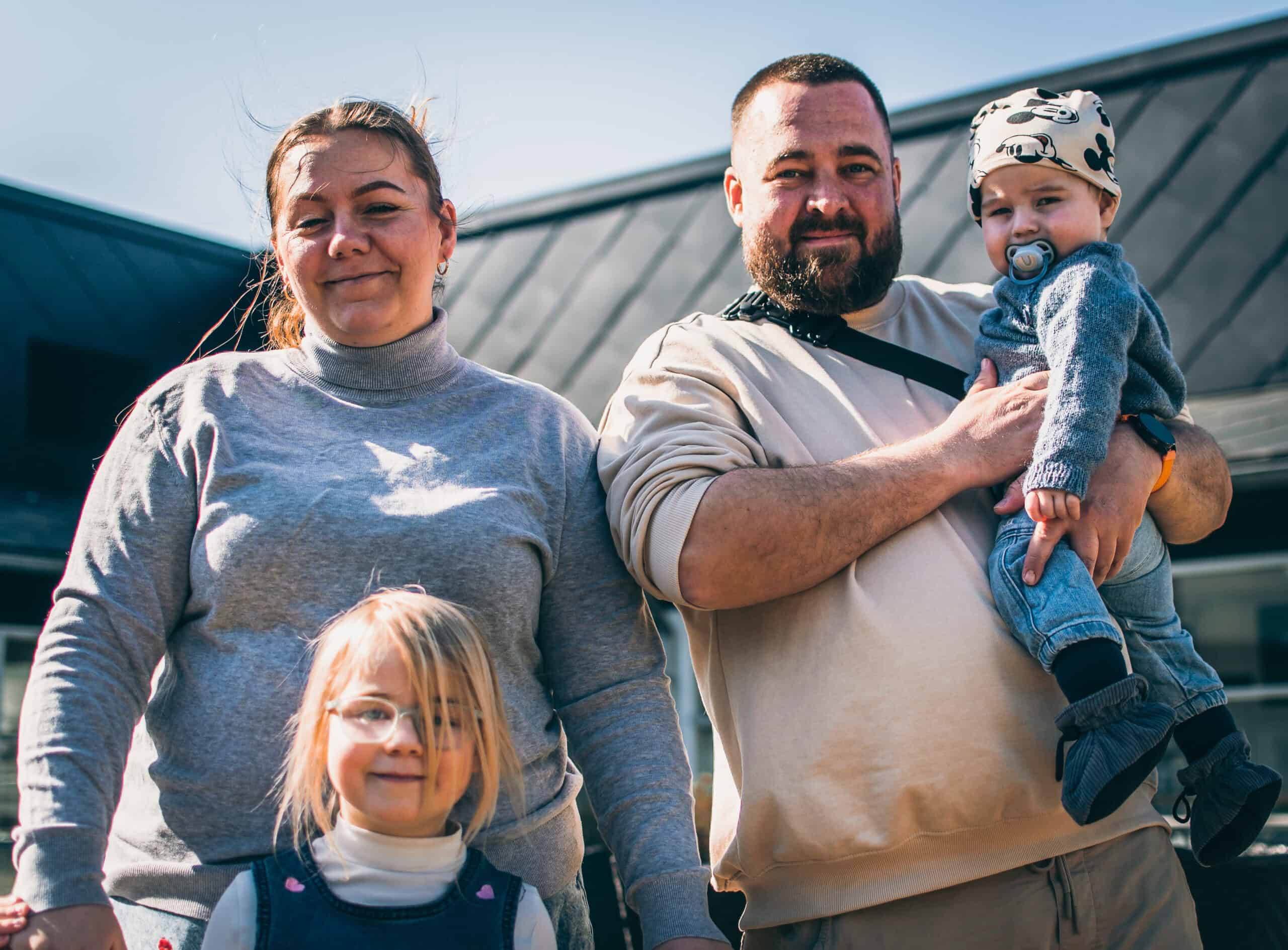 Hele familien Lindeberg Balle ses samlet. Til venstre står mor Rebecca med storesøster Kastanie foran sig. Til højre står far Kåre og holder Vester.