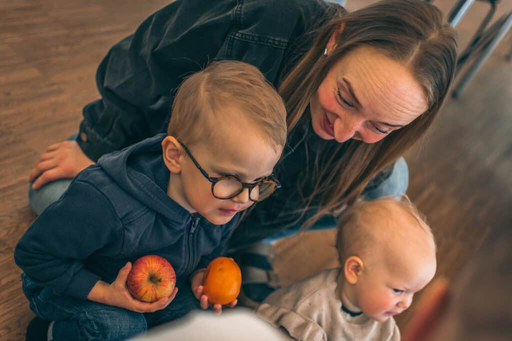Otto sidder sammen med sin mor, Karen, og sin lillesøster, Ena. I hænderne holder han et æble og en mandarin.