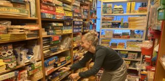 Legetøj som løftestang Pipper Holten fra Legeteket i Odense leder efter legetøj på tætpakkede reolhylder