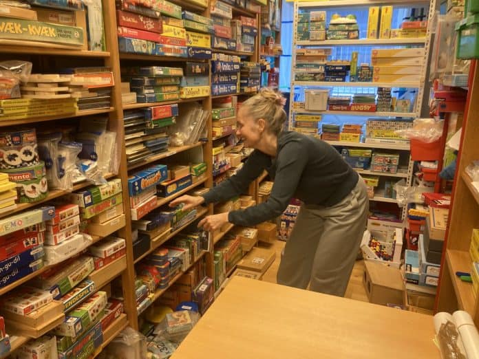 Pipper Holten fra Legeteket i Odense leder efter legetøj på tætpakkede reolhylder