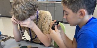 Leder: Leg skaber identitet og udvikling 2 drenge nærstuderer en stensamling med lup og små kikkerter